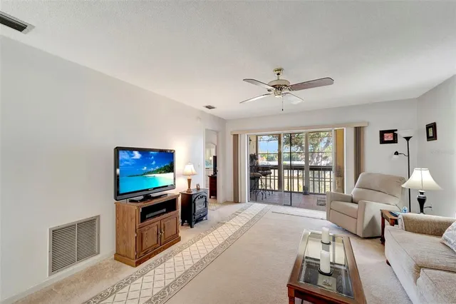 a living room with furniture a flat screen tv and floor to ceiling window