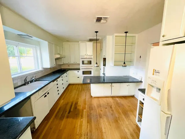 a large kitchen with kitchen island a large counter space a sink a refrigerator and windows