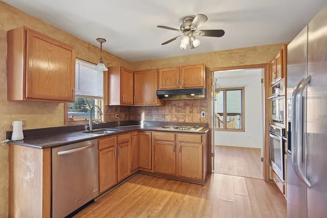 a kitchen with stainless steel appliances granite countertop a sink cabinets and wooden floor