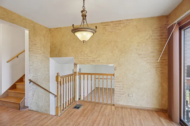 a view of a hallway with wooden floor and chandelier