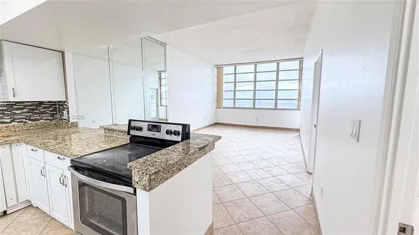 a kitchen with granite countertop a stove a sink and a refrigerator