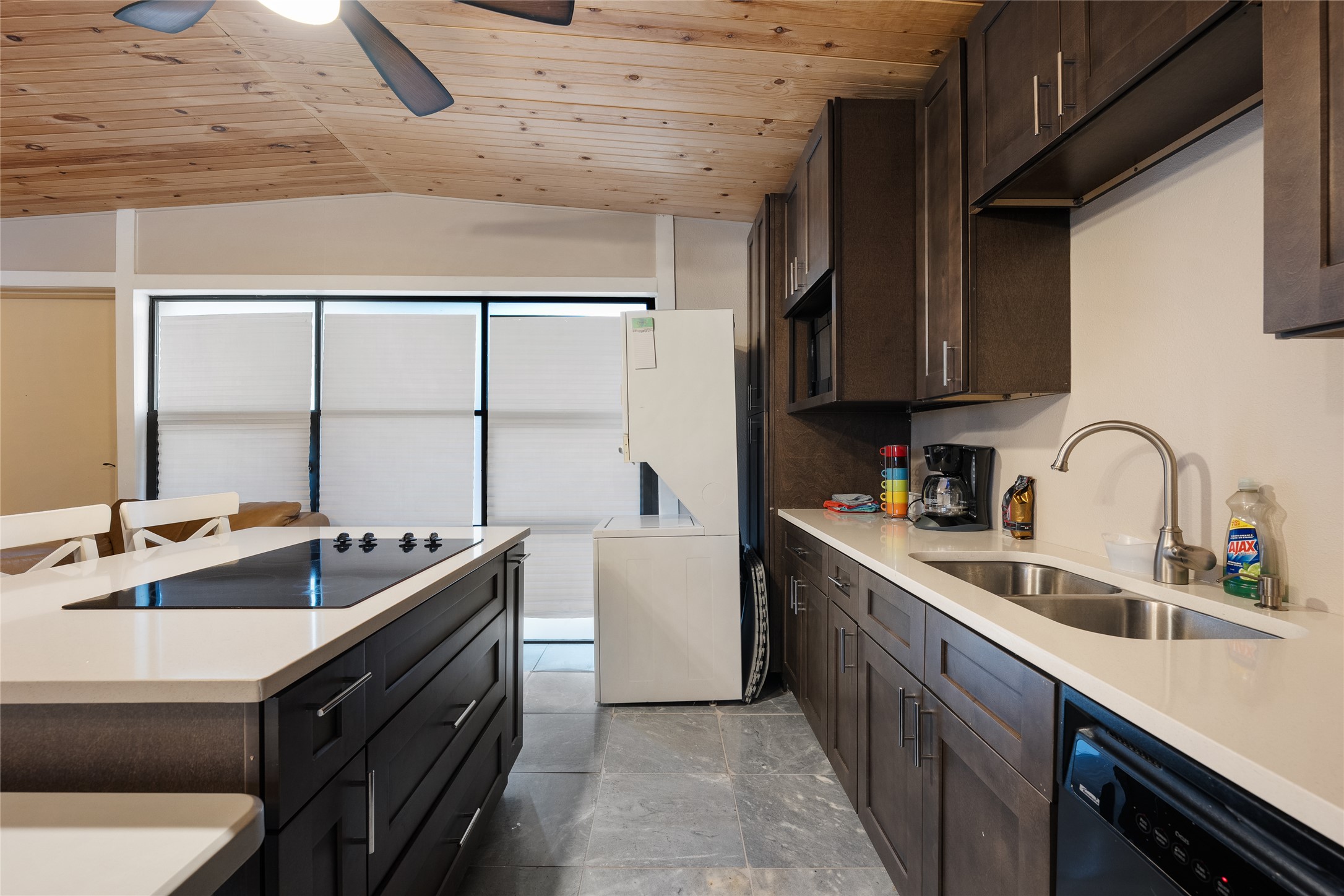 301 Oak Ridge Road Georgetown, TX 78628 - Photo 36 of 38 Kitchen featuring dark wood-finish cabinetry, light countertops, an undermount double-basin sink with a gooseneck faucet, a built-in cooktop on the island, and plank wood-finish ceilings with a ceiling fan