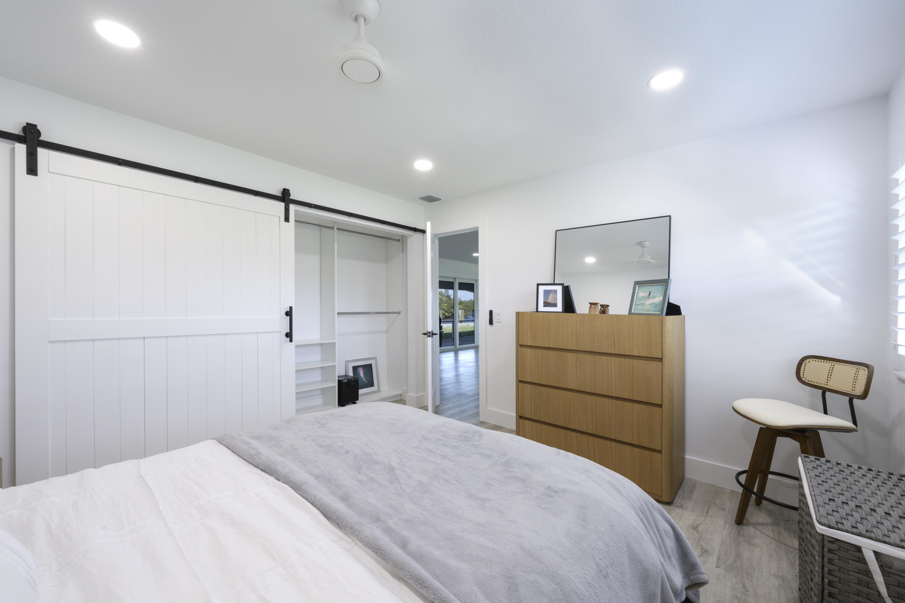 8585 Southeast Palm Street Hobe Sound, FL 33455 - Photo 22 of 43 a bedroom with a bed and a chandelier