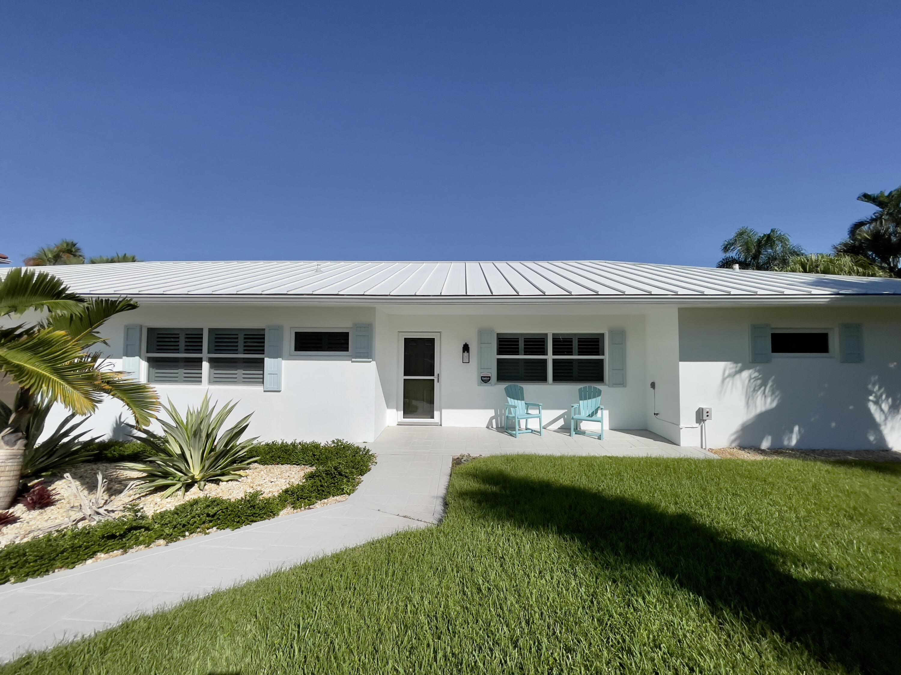 8585 Southeast Palm Street Hobe Sound, FL 33455 - Photo 5 of 43 a front view of a house with a yard table and chairs