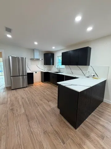 a kitchen with a wooden floor and black cabinets