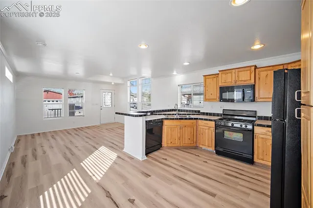 a kitchen with stainless steel appliances granite countertop a refrigerator a sink dishwasher a stove with wooden cabinets and floor