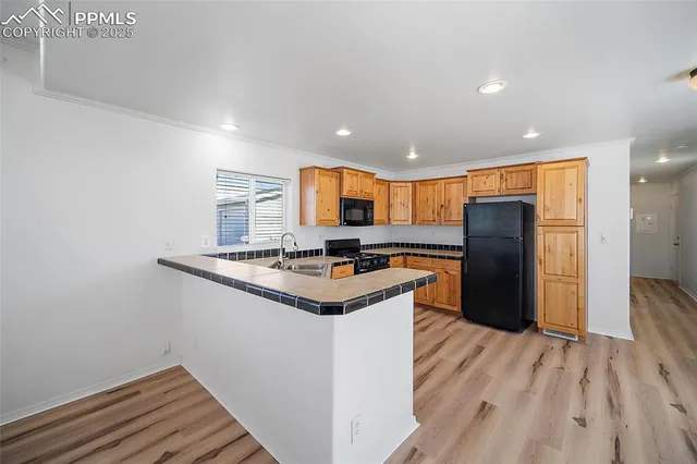 a kitchen with stainless steel appliances granite countertop a refrigerator a sink and a stove with wooden floor