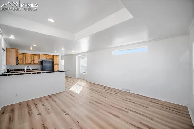 a view of kitchen with stainless steel appliances wooden floor and large window