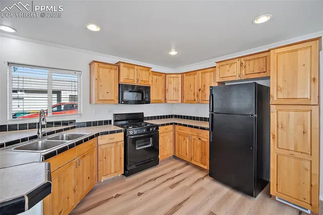 a kitchen with stainless steel appliances granite countertop a refrigerator a sink dishwasher a stove and white countertops with wooden floor