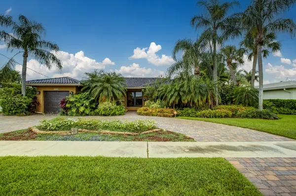 a white house with a yard and palm trees
