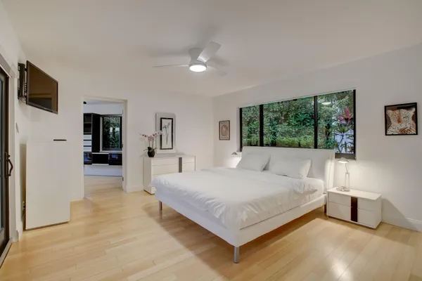 a bedroom with a large bed a flat tv screen and a dresser