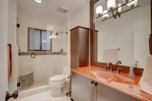 a bathroom with a granite countertop sink toilet a mirror and shower
