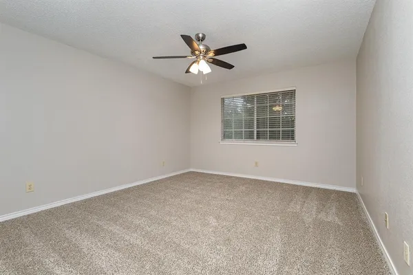 an empty room with a window and a fan