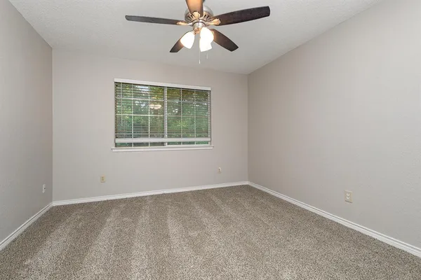 an empty room with a window and a fan