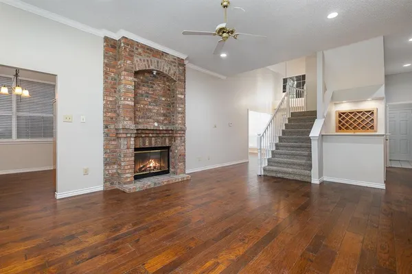 an empty room with wooden floor fireplace and windows