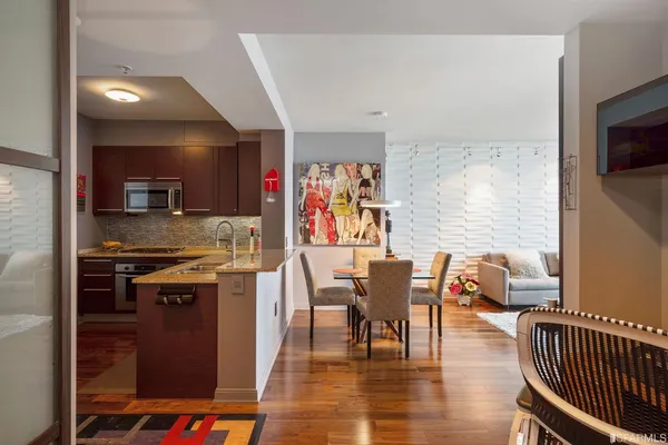 a kitchen with stainless steel appliances granite countertop a stove top oven a sink a dining table and chairs with wooden floor