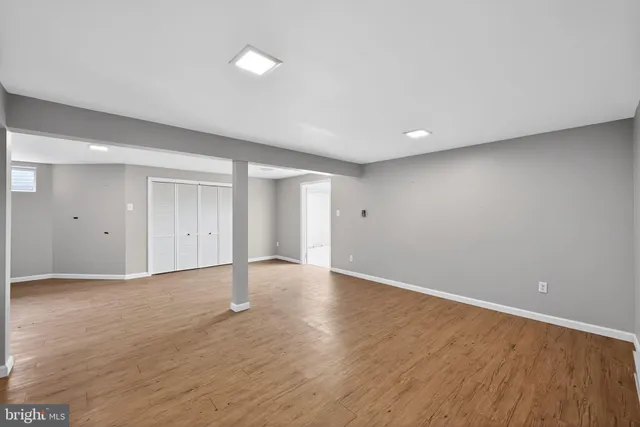a view of an empty room with wooden floor and closet