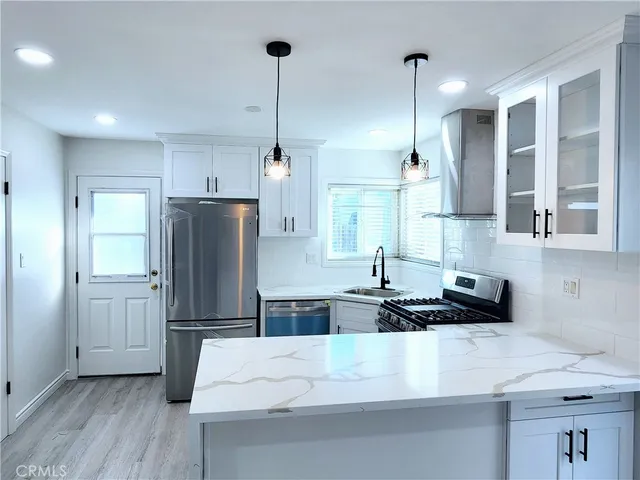 a kitchen with stainless steel appliances a refrigerator sink and wooden floor