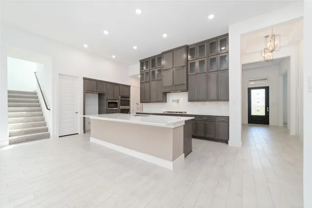 a large white kitchen with a sink and dishwasher a stove top oven with wooden floor
