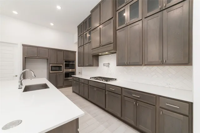a kitchen with stainless steel appliances a sink dishwasher a refrigerator and cabinets with wooden floor