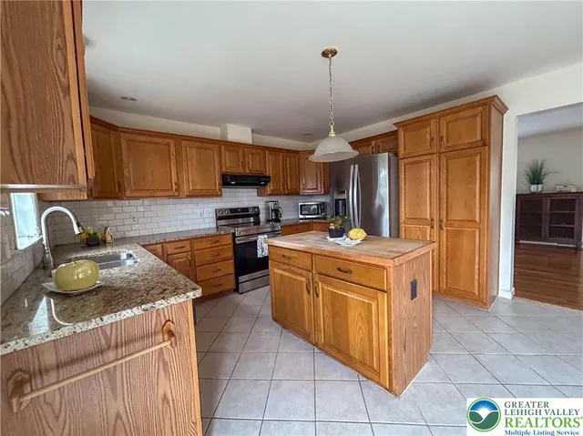 a kitchen with stainless steel appliances granite countertop a sink counter space cabinets and a stove