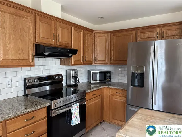 a kitchen with granite countertop a refrigerator stove and oven