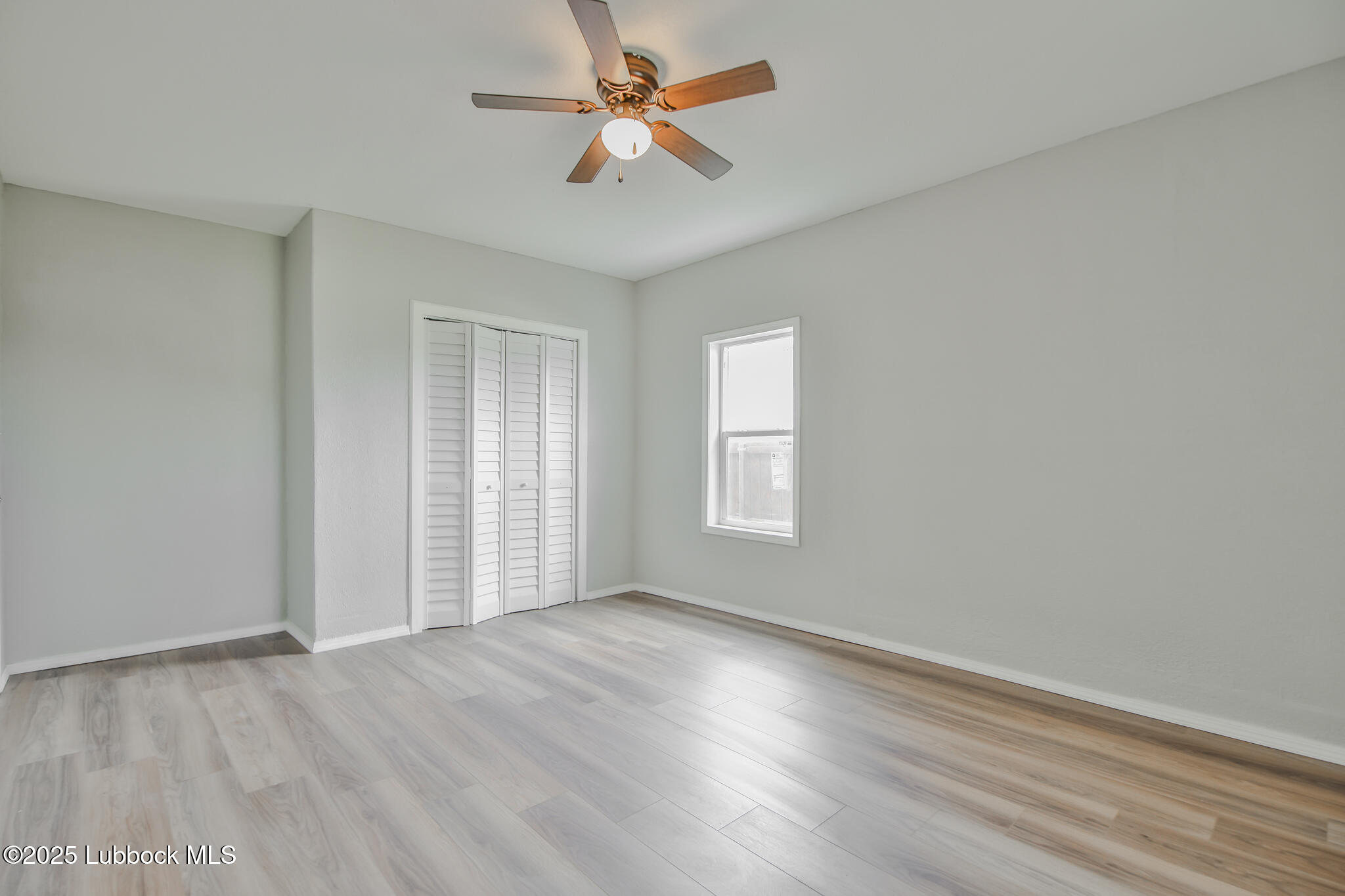 115 Yonkers Street Plainview, TX 79072 - Photo 16 of 28 an empty room with wooden floor fan and windows