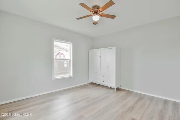 an empty room with wooden floor ceiling fan and windows