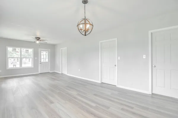 a view of an empty room with wooden floor and window