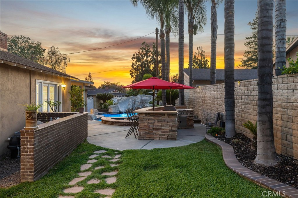 222 South Wagonwheel Road Glendora, CA 91741 - Photo 65 of 70 a view of a patio with table and chairs under an umbrella with a fire pit and a yard