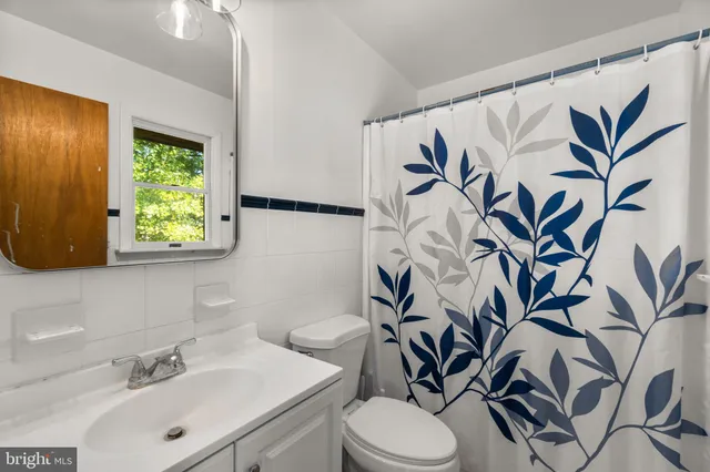 a bathroom with a sink a toilet a mirror and shower curtain