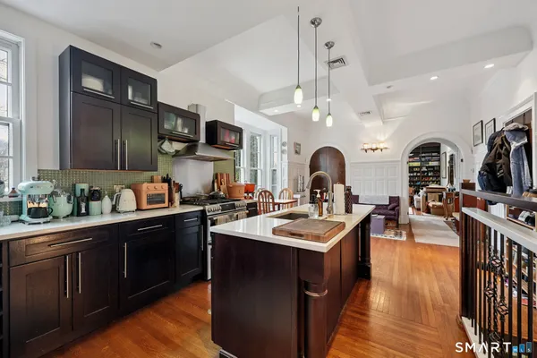 a very nice looking kitchen with granite countertop a stove a sink a refrigerator and dining table