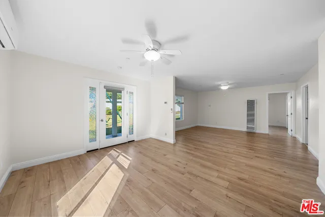 a view of an empty room with a window and wooden floor