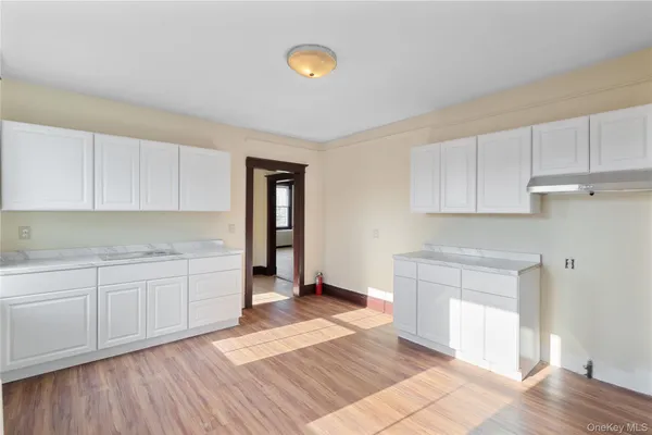 a kitchen with granite countertop a stove a sink and white cabinets with wooden floor