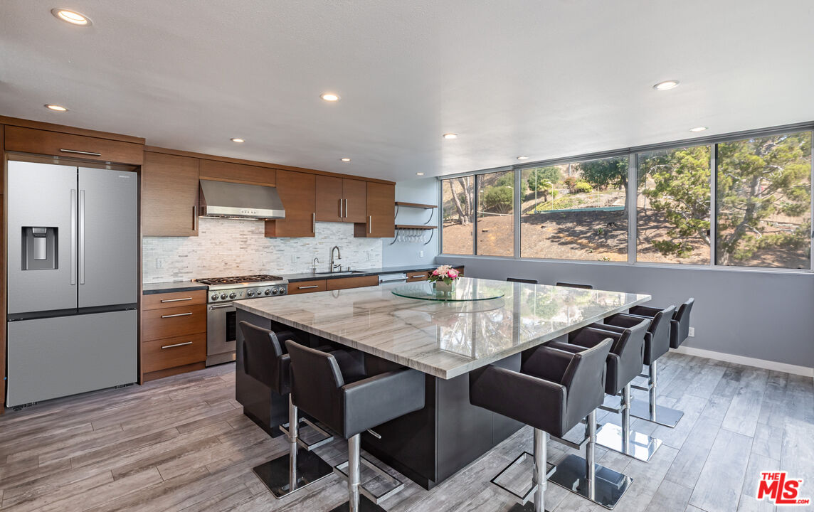 17352 Sunset Boulevard, Unit 202 Pacific Palisades, CA 90272 - Photo 10 of 30 a kitchen with granite countertop counter space dining table and stainless steel appliances