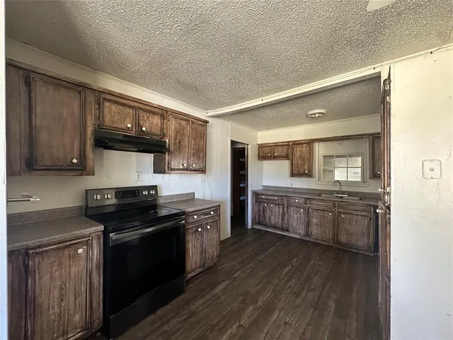 a kitchen with stainless steel appliances granite countertop wooden cabinets a stove top oven a sink and dishwasher