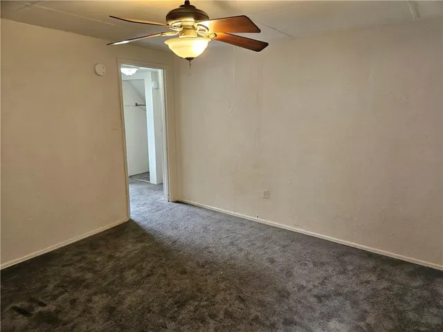 an empty room with a chandelier fan and windows