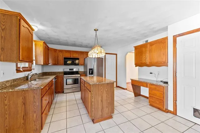 a kitchen with stainless steel appliances granite countertop a refrigerator a sink dishwasher stove and oven