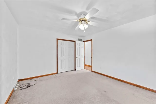 a view of an empty room with wooden floor and a ceiling fan