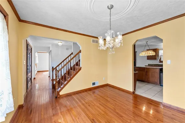 a view of a room with wooden floor staircase and a chandelier