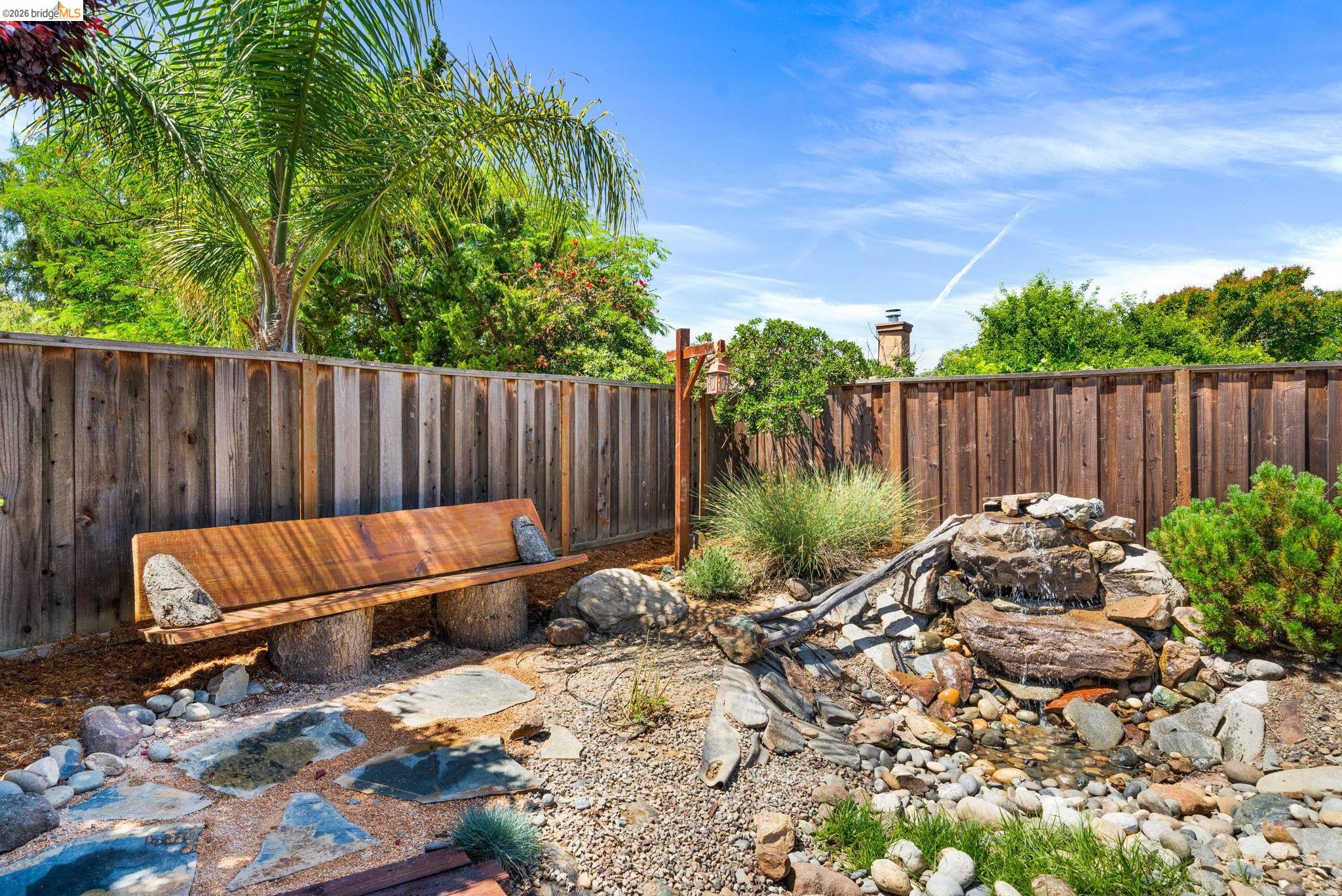 1186 El Rio Court Livermore, CA 94551 - Photo 36 of 60 Outdoor space featuring a natural rock water feature, a custom wooden bench with tree stump supports, and a privacy fence