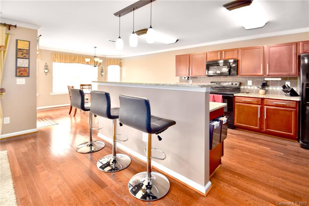 10010 Rocky Ford Club Road Charlotte, NC 28269 - Photo 9 of 24 a kitchen with stainless steel appliances granite countertop a stove top oven a sink a dining table and chairs with wooden floor