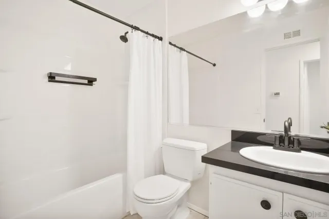 a bathroom with a sink a toilet a mirror and shower