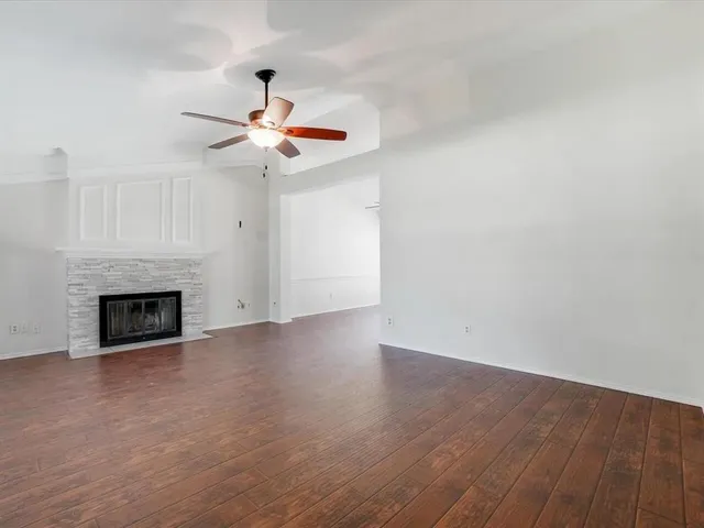 a view of an empty room with wooden floor and a fireplace