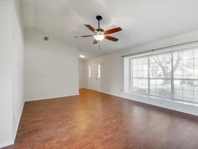 a view of an empty room with window and a kitchen
