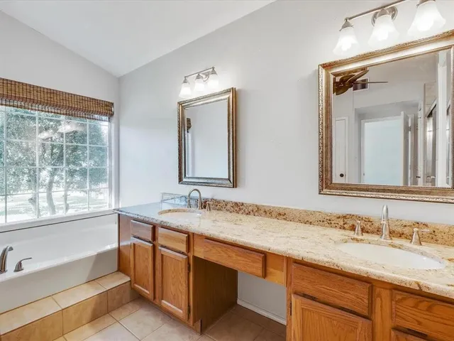 a bathroom with a granite countertop sink mirror and a bath tub