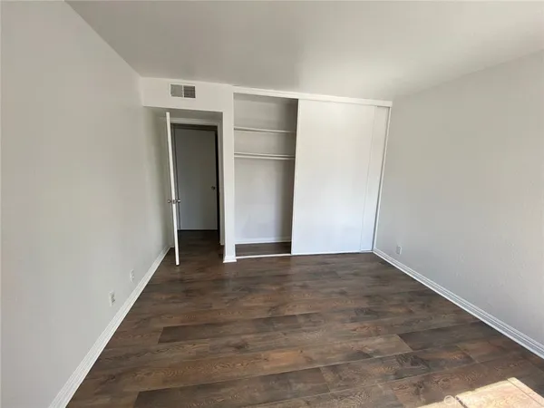 a view of an empty room with wooden floor and closet