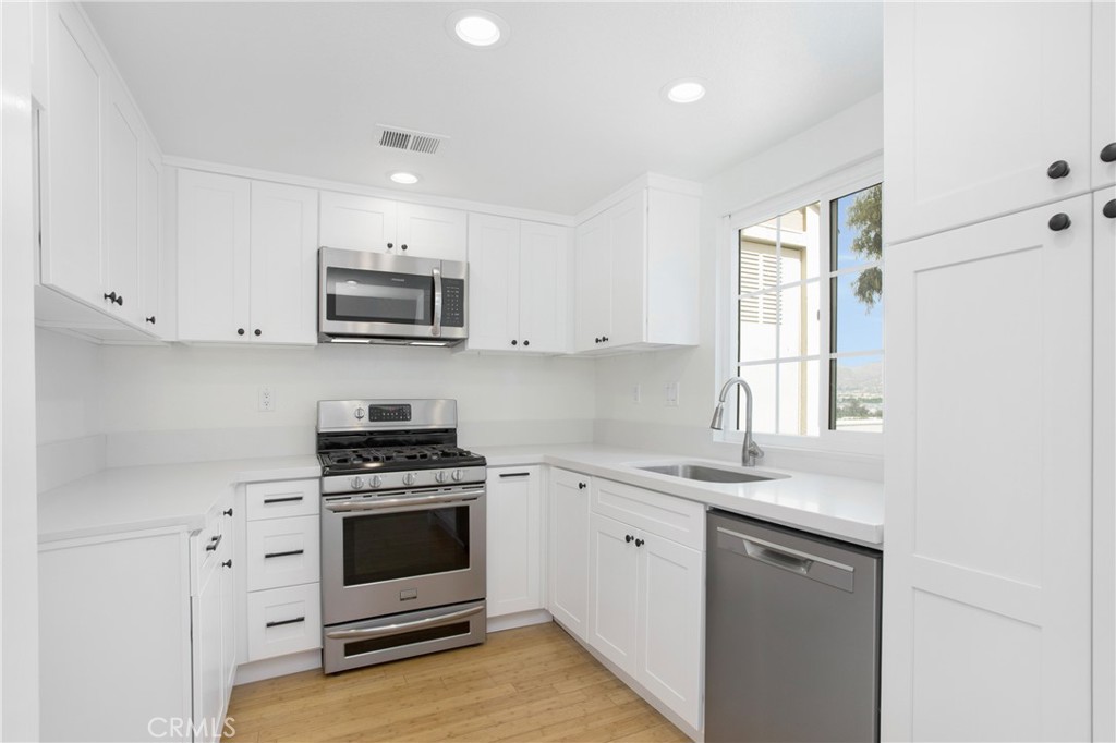 20006 Shamrock, Unit 10 Lake Forest, CA 92630 - Photo 9 of 25 a kitchen with granite countertop a stove a sink and a microwave