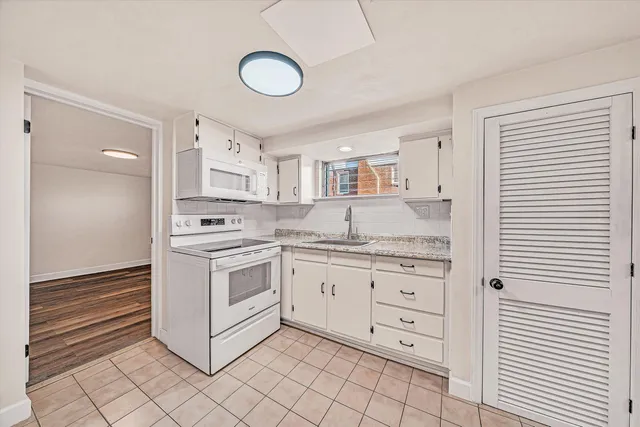 a kitchen with granite countertop white cabinets and white appliances