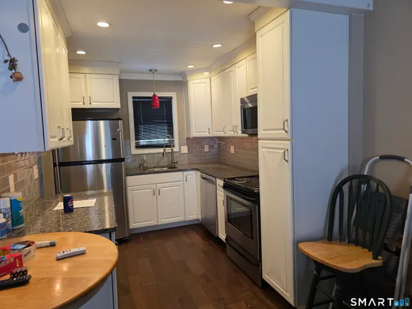 a kitchen with stainless steel appliances granite countertop a refrigerator a stove and a sink